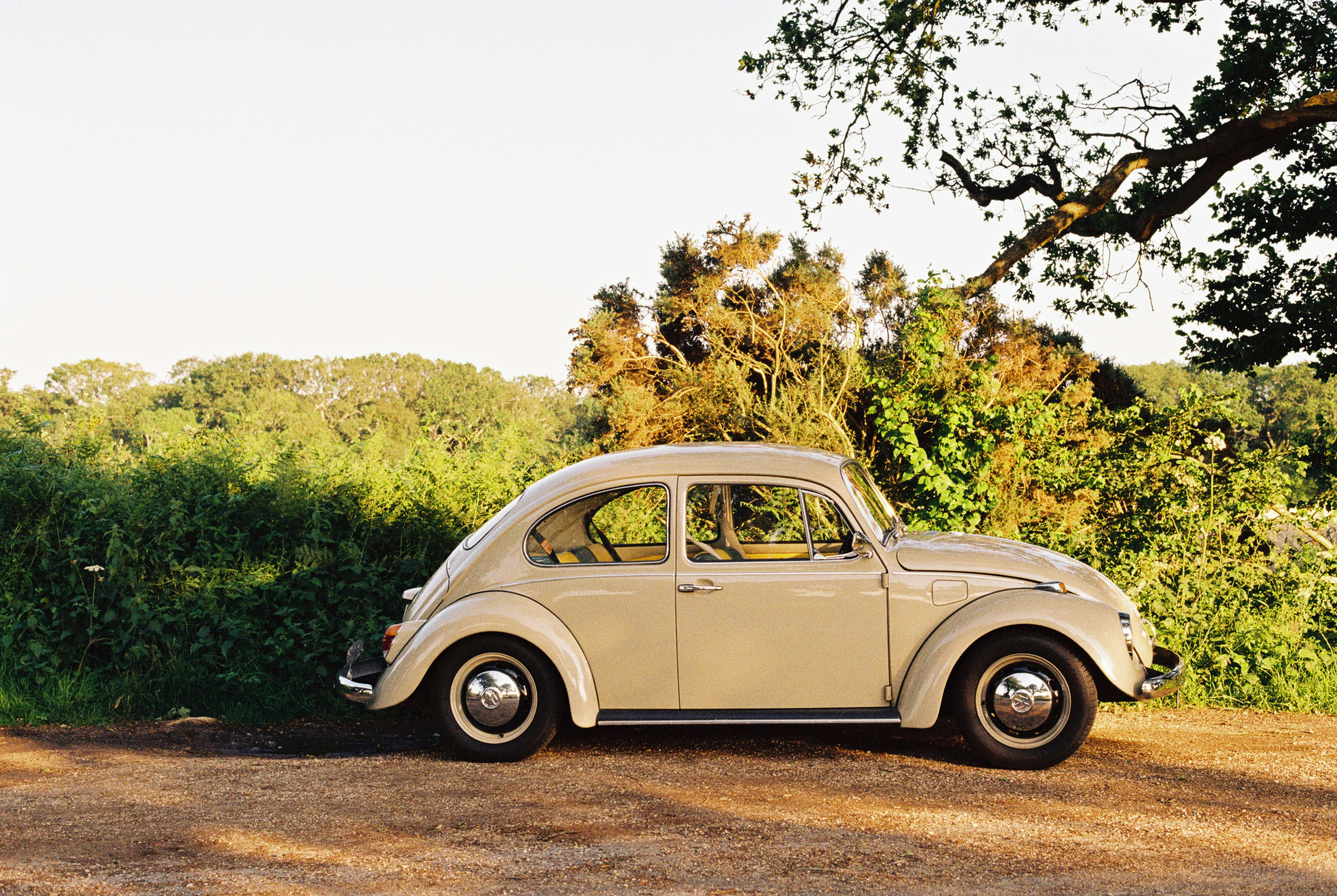 white volkswagen beetle parked on brown dirt road during daytime